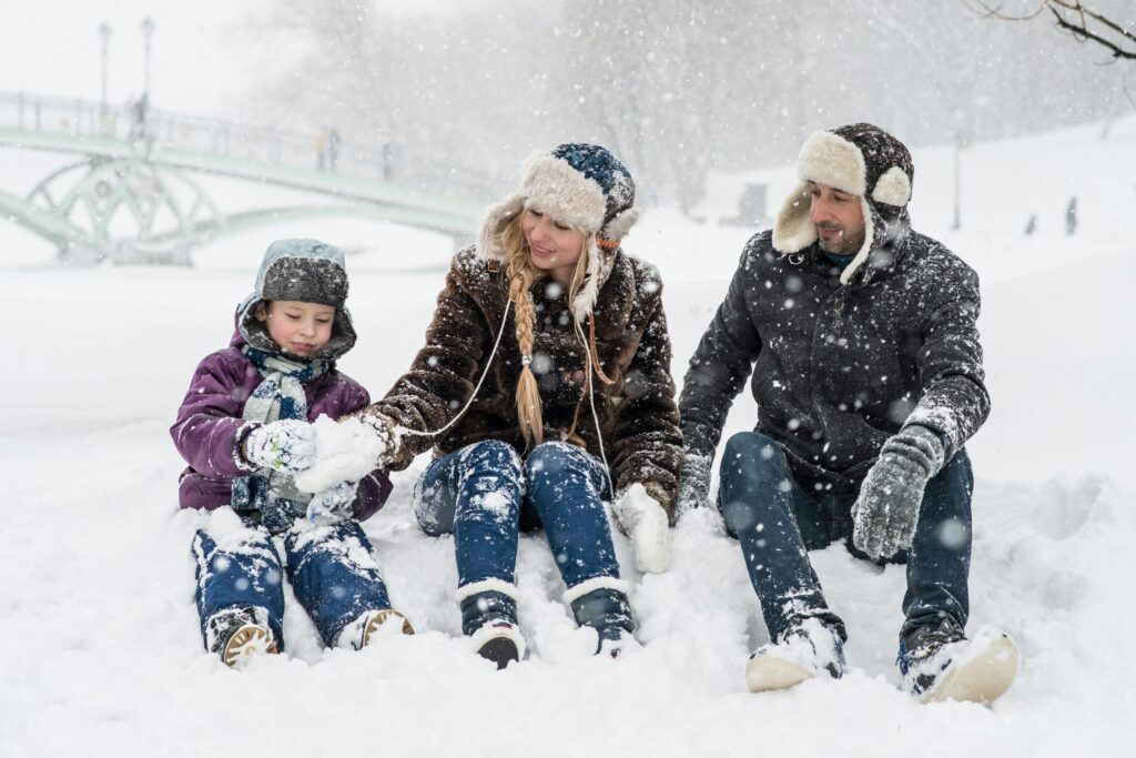 Happy family enjoying playful time in snowy winter park, capturing joyful moments in nature.